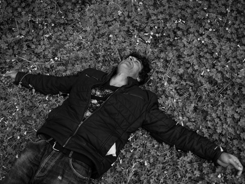 A man from Afghanistan lies down in a land. Lesvos, Greece, The Island, 2020