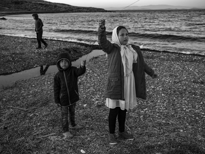 Two Afghan children fly a kite together. Lesvos, Greece, The Island, 2020